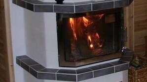 A fireplace with a tiled surround and a blue decorative element on top. - Nuppulanranta cottage by lake (Jamsa)