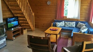 A wooden interior with a sofa, chairs, a TV, and a staircase. - Nuppulanranta cottage by lake (Jamsa)