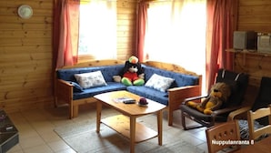 A cozy cabin interior with a blue sofa, a wooden coffee table, and a lion plush toy. - Nuppulanranta cottage by lake (Jamsa)