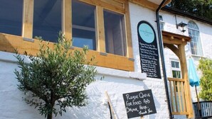 A building with a signboard reading "Please queue for food and drink here. Thank you."