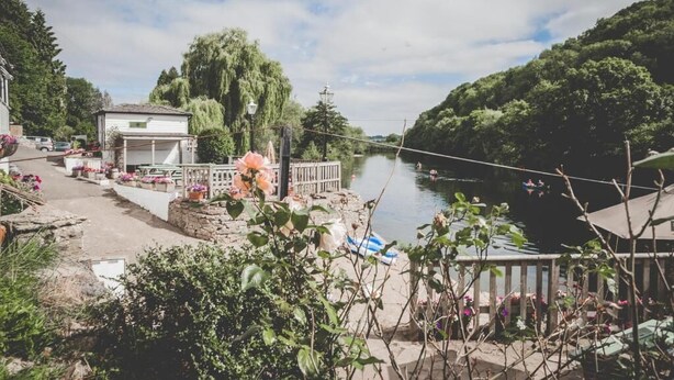 A riverside view with a gazebo, flower beds, and a dock.