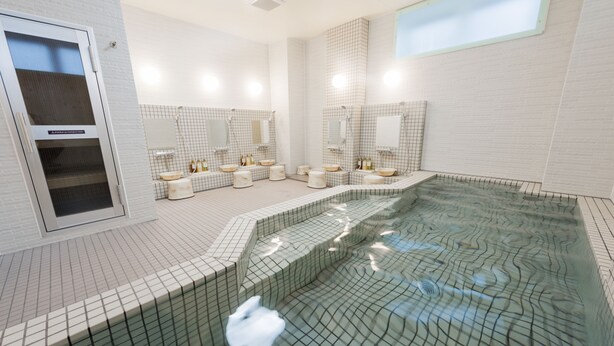 A modern bathroom with a large bathtub, multiple sinks, and a glass-enclosed shower area. - Hotel Sugita (Tomakomai)