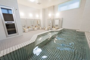 Un baño moderno con una bañera grande, varios lavamanos y una zona de ducha con mampara de vidrio.