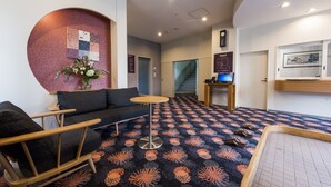 A hotel lobby with a patterned carpet, seating area, and a staircase. - Hotel Sugita (Tomakomai)