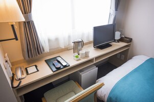 Una habitación de hotel con escritorio, televisor, teléfono, cafetera y cama.