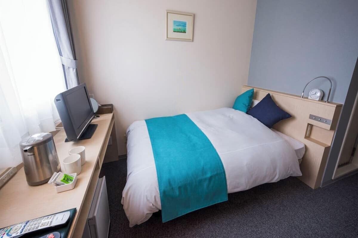 Une chambre d’hôtel avec un lit, un bureau doté d’une machine à café, une télévision et un petit tableau accroché au mur.