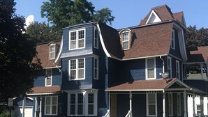 A two-story house with a porch and a fire hydrant in the foreground. - Roe Summer Cottage, Suite B (Watkins Glen)