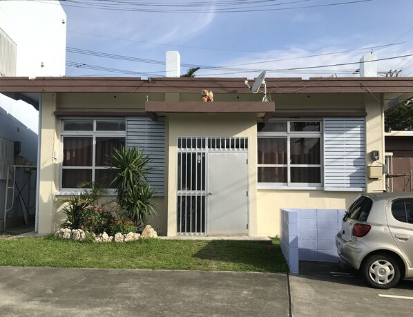 A two-story house with a gated entrance, a satellite dish, and a parked car.