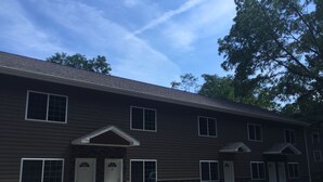 A two-story building with a symmetrical facade, featuring a central entrance with a small overhang, flanked by two doors. - Watkins Glen 3-Bedroom Suites Unit 5 (Watkins Glen)