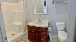 A bathroom with a shower, sink, toilet, and a mirror. - Watkins Glen 3-Bedroom Suites Unit 5 (Watkins Glen)