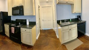 A compact kitchen with white cabinets, a black refrigerator, a microwave, a stove, and a dishwasher. - Watkins Glen 3-Bedroom Suites Unit 5 (Watkins Glen)