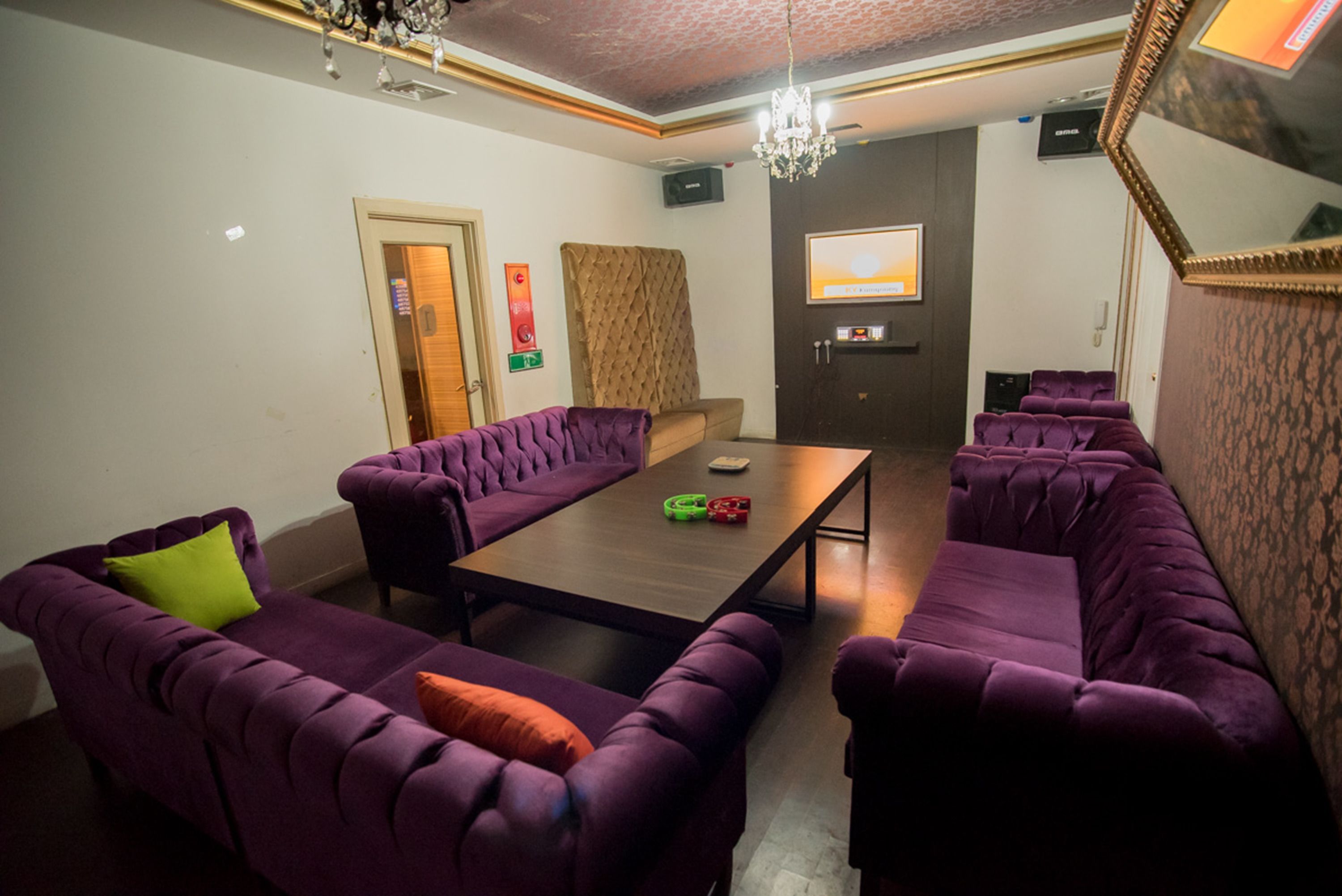 A room with purple upholstered sofas, a wooden coffee table, and a chandelier.