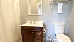 Ein Badezimmer mit Duschvorhang, Waschbecken mit Spiegel darüber, Toilette und Handtuchhalter.