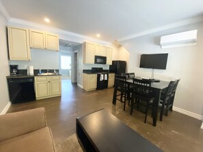 A modern kitchen with white cabinets, a black refrigerator, and a dining area with a dark wooden table and chairs.