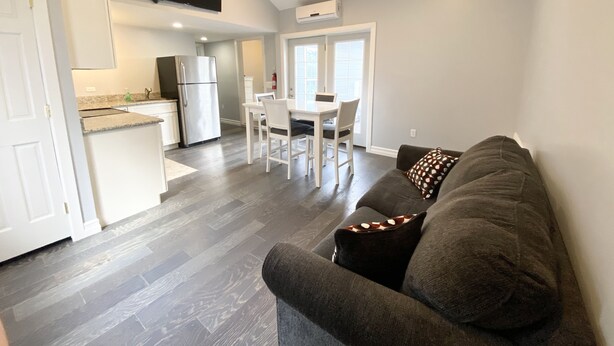 A modern kitchen with a built-in refrigerator, a dining area with a white table and chairs, and a gray sofa with patterned pillows. - 411 S. Madison Avenue (Watkins Glen)