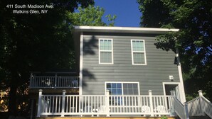 A two-story house with a front porch and a small deck. - 411 S. Madison Avenue (Watkins Glen)