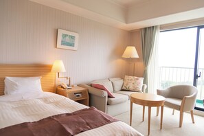 Ein Hotelzimmer mit Bett, Sofa, einem kleinen Tisch und einem Balkon mit Blick.