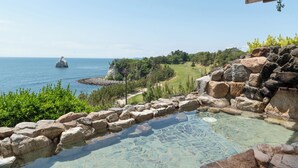 A clear view of a swimming pool with a stone border, surrounded by greenery and a view of the sea. - ONAHAMA OCEAN HOTEL & GOLF CLUB (Iwaki)