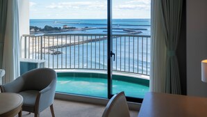 A room with a large window offering a view of the sea and a pier. There are two chairs and a table in the room. - ONAHAMA OCEAN HOTEL & GOLF CLUB (Iwaki)