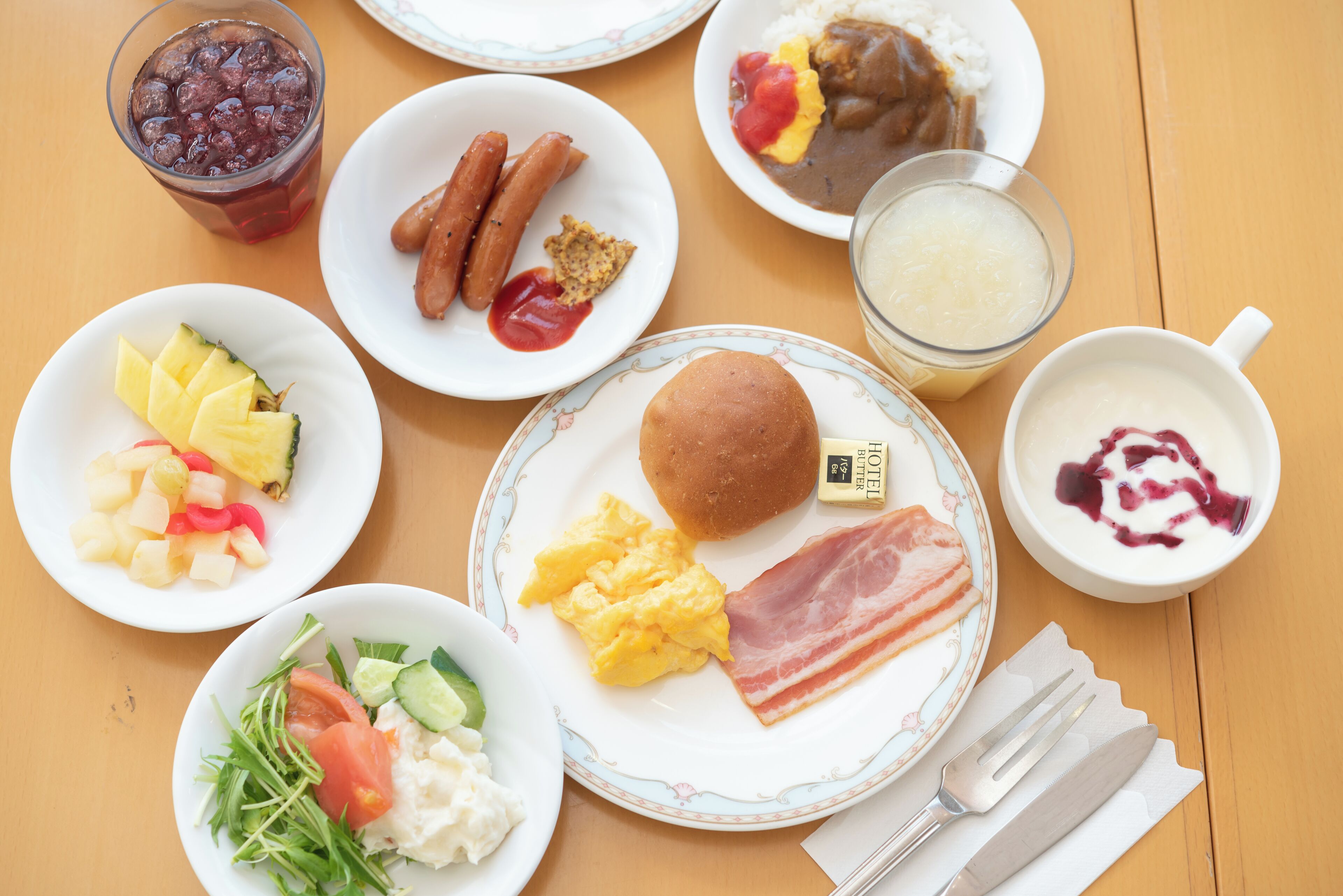 A table with breakfast items including eggs, bacon, sausages, and various fruits.