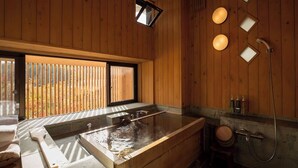 Una cabaña de madera con un jacuzzi, una ventana con persianas y un rincón para la ducha.