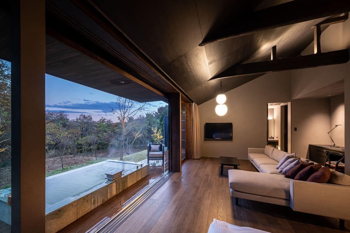 Una sala de estar moderna con un amplio ventanal, un sofá, un televisor y piso de madera.