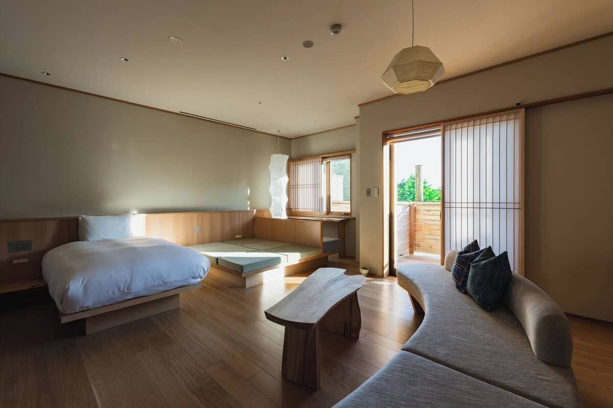 Un dormitorio moderno con cama, zona de estar y vistas a zonas verdes.