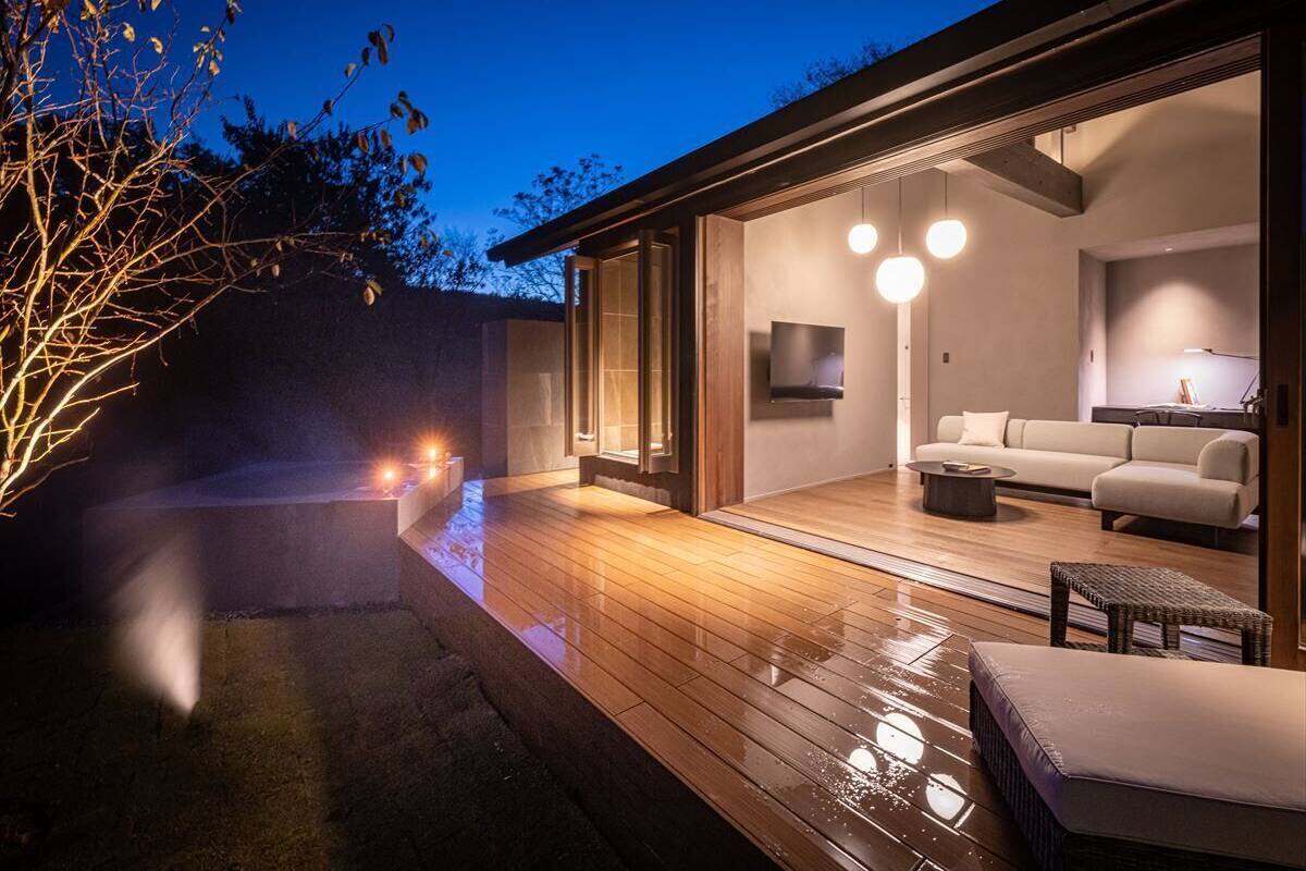 Un espacio exterior moderno con terraza de madera, un sofá y una mesa de centro.