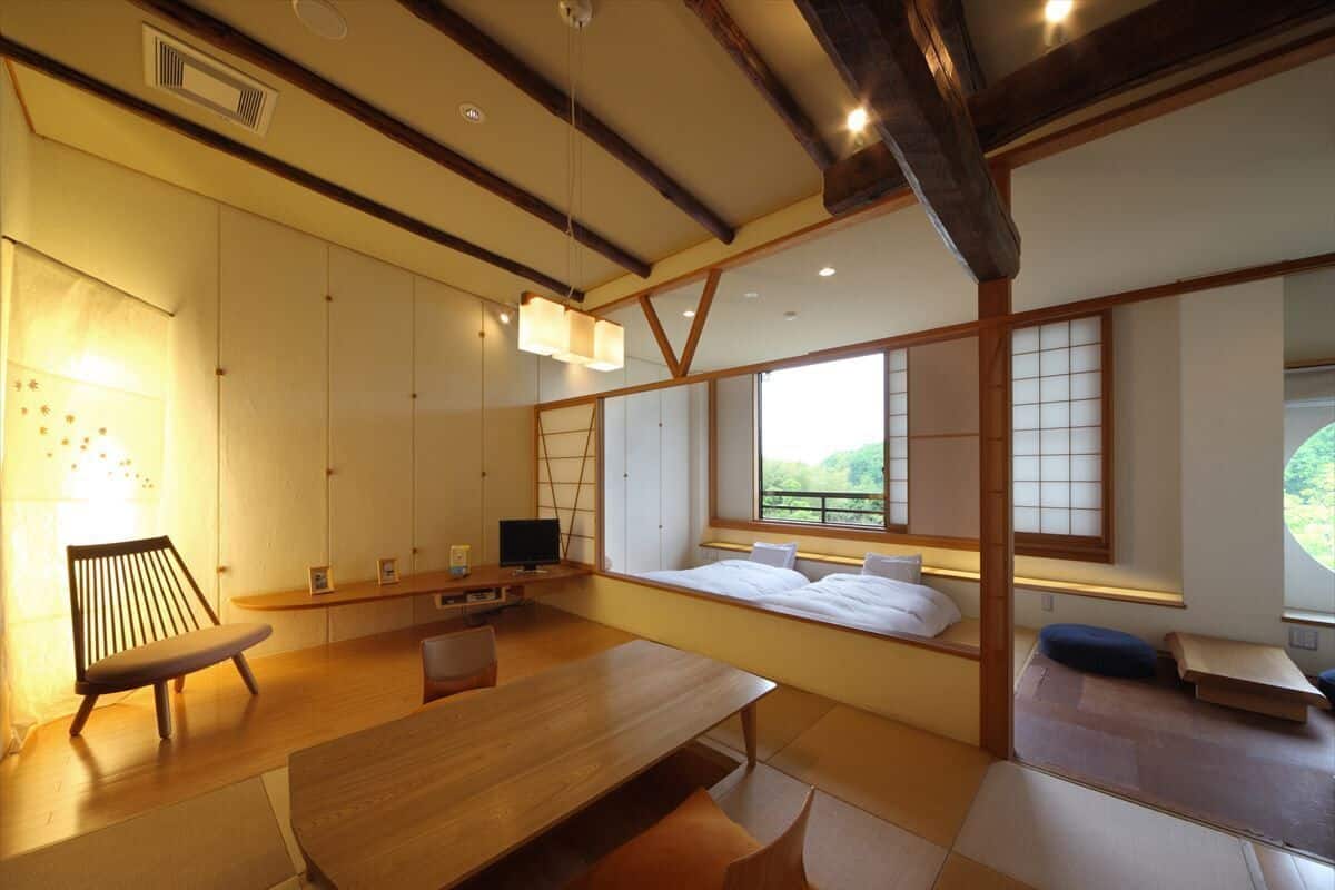 Una habitación tradicional japonesa con suelo de tatami, una mesa baja, un banco acolchado y puertas correderas.