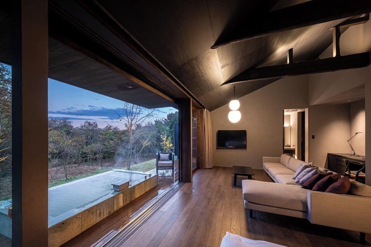 Una sala de estar moderna con un ventanal grande, un sofá, un televisor y un escritorio.