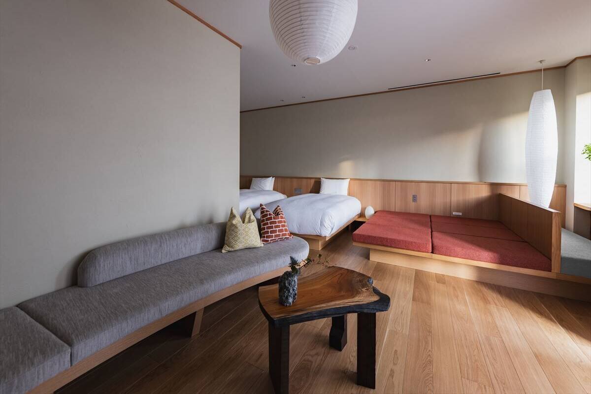 Una habitación moderna con sofá, cama, una mesita y una lámpara colgante.