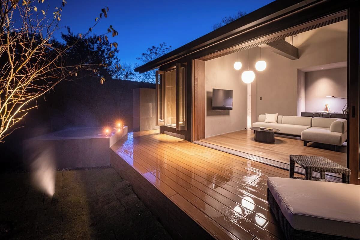 Una casa moderna con terraza de madera, sofá y televisor en la sala.