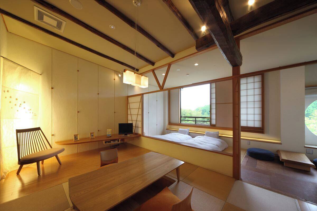 Una habitación de estilo japonés tradicional con suelo de tatami, una mesa baja, una cama con futón y puertas correderas.
