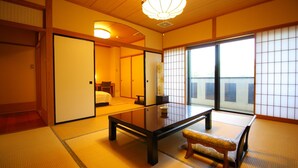 A traditional Japanese room with tatami flooring, a low table, a bench, sliding doors, and a view through a shoji screen.