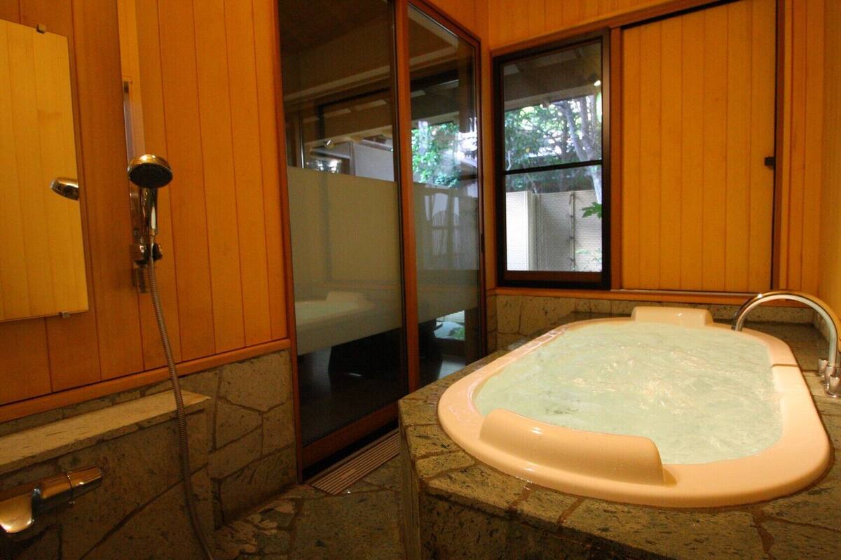 Un baño con bañera, ducha y ventana.