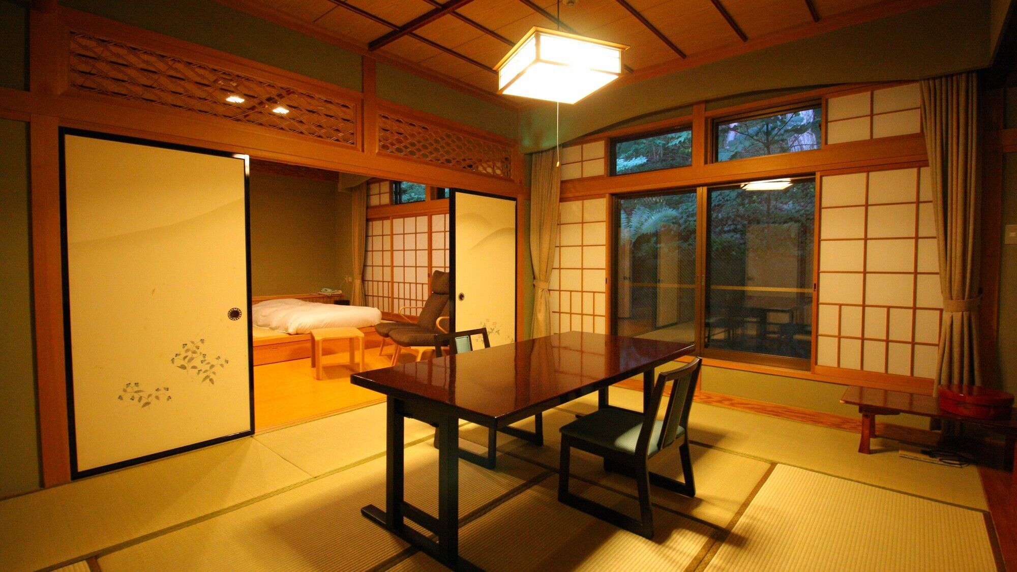 Una habitación tradicional japonesa con suelo de tatami, una mesa baja y puertas correderas.