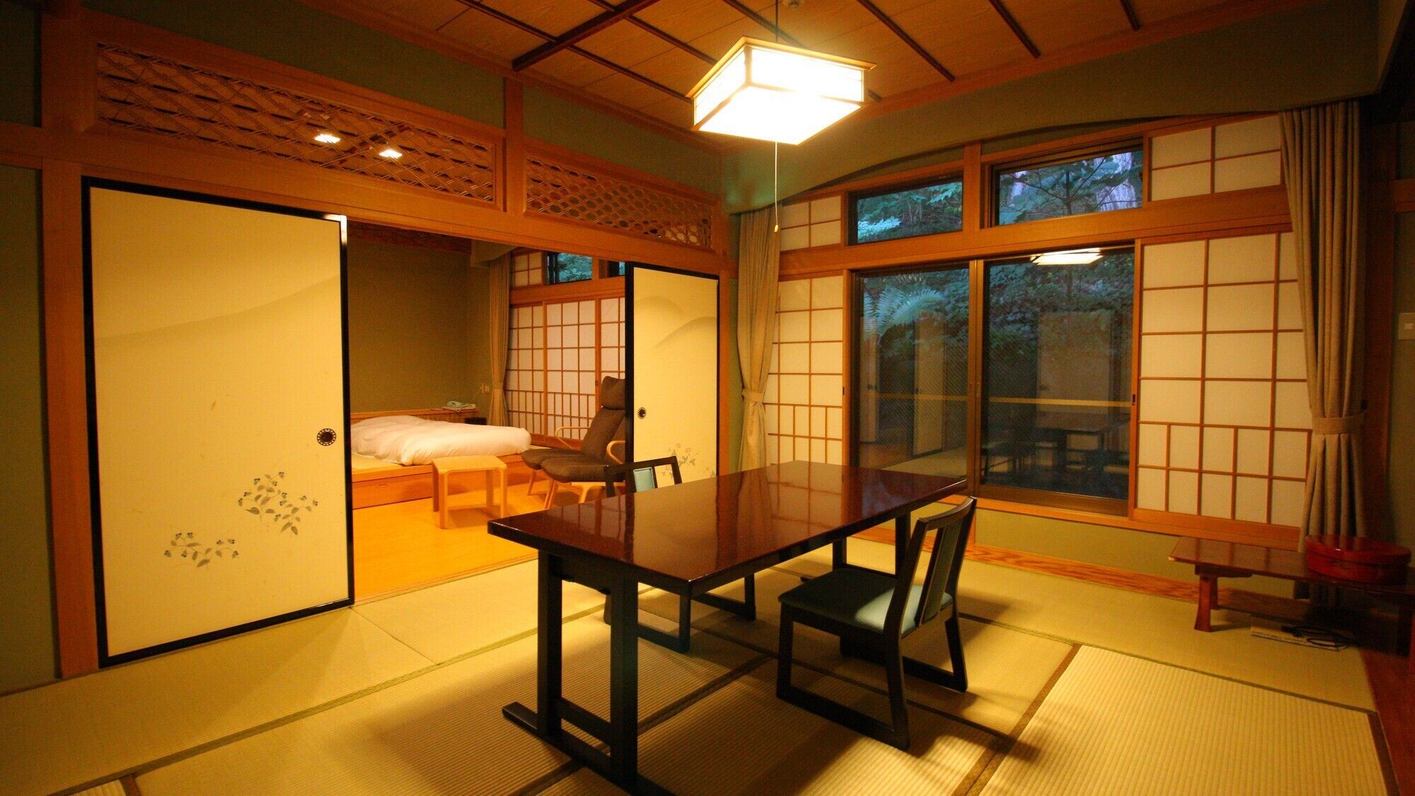 Una habitación japonesa tradicional con suelo de tatami, una mesa baja y puertas correderas.