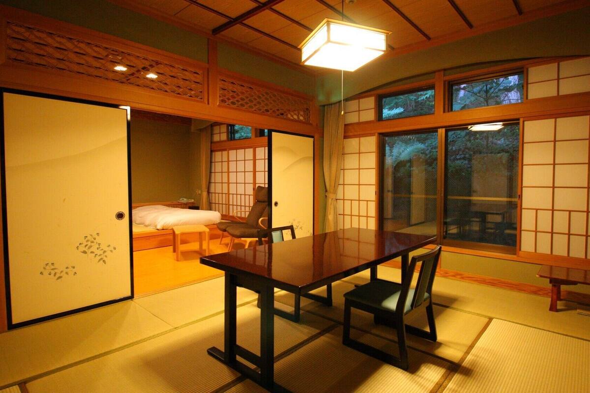 Una habitación japonesa tradicional con suelo de tatami, una mesa baja y puertas correderas.