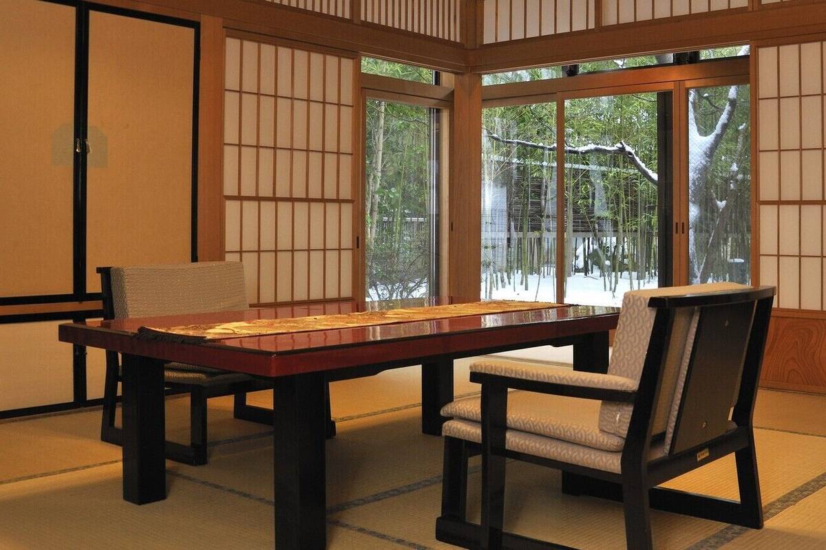 Una habitación japonesa tradicional con suelo de tatami, una mesa baja y puertas correderas.