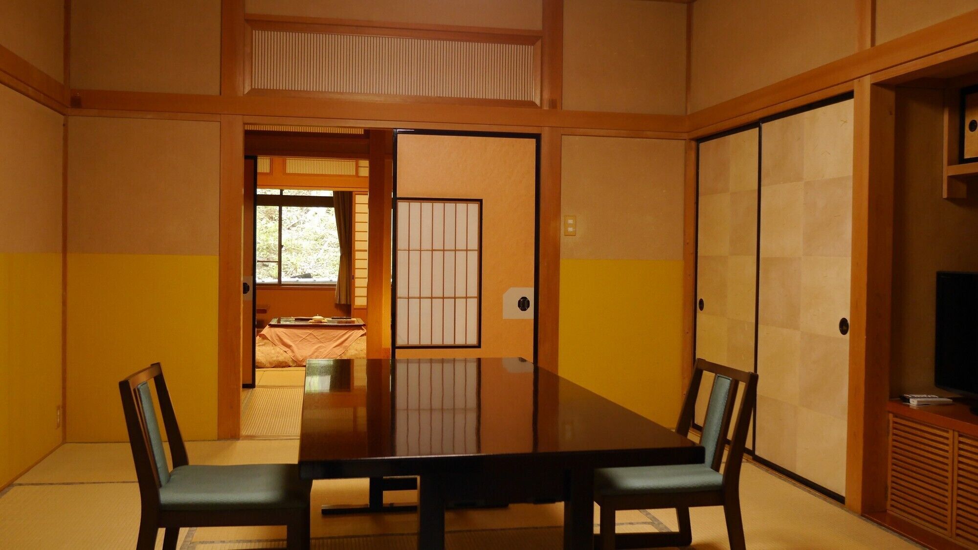 Una habitación tradicional japonesa con suelo de tatami, una mesa baja y puertas correderas.