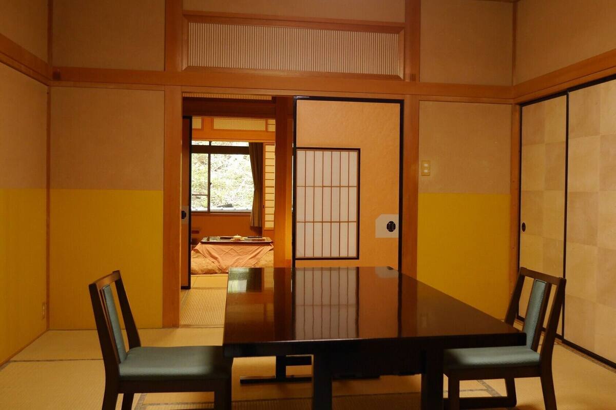Una habitación tradicional japonesa con suelo de tatami, una mesa baja y puertas correderas.