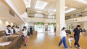 Un hall d’entrée spacieux avec un plafond haut, un escalier central et un comptoir de réception.
