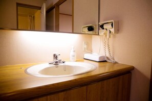 A bathroom with a white sink, a mirror, a hand dryer, and a telephone.