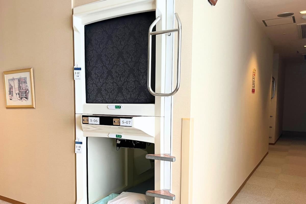 Una habitación de hospital con una cama, un televisor y una puerta con picaporte.