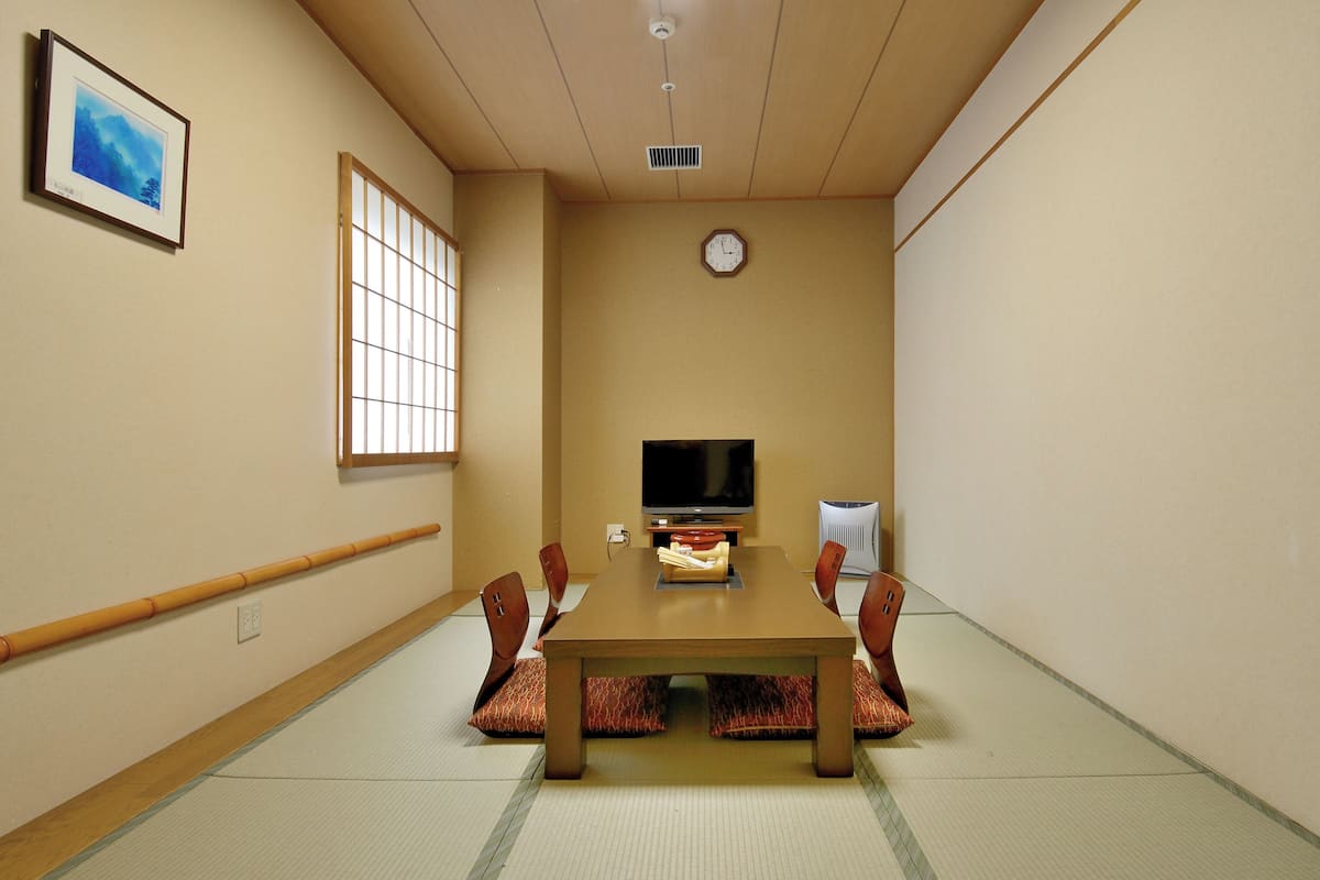 Un salón de conferencias con una mesa de madera, sillas, un televisor y un reloj en la pared.