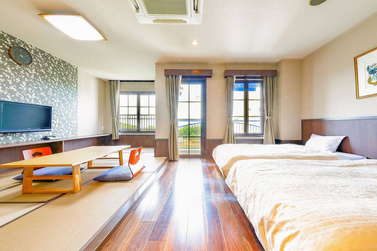 Une chambre d’hôtel équipée d’un lit, d’un bureau, d’une chaise, d’une télévision et d’une fenêtre avec des rideaux.