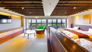 A modern hotel room with a large bed, a seating area with a green chair, and a view of the outdoors through large windows. - Ooedo Onsen Monogatari Hotel Reoma no Mori (Marugame)