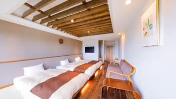 A hotel room with a long wooden ceiling, a bed with white and brown bedding, a small wooden stool, and a framed picture on the wall.