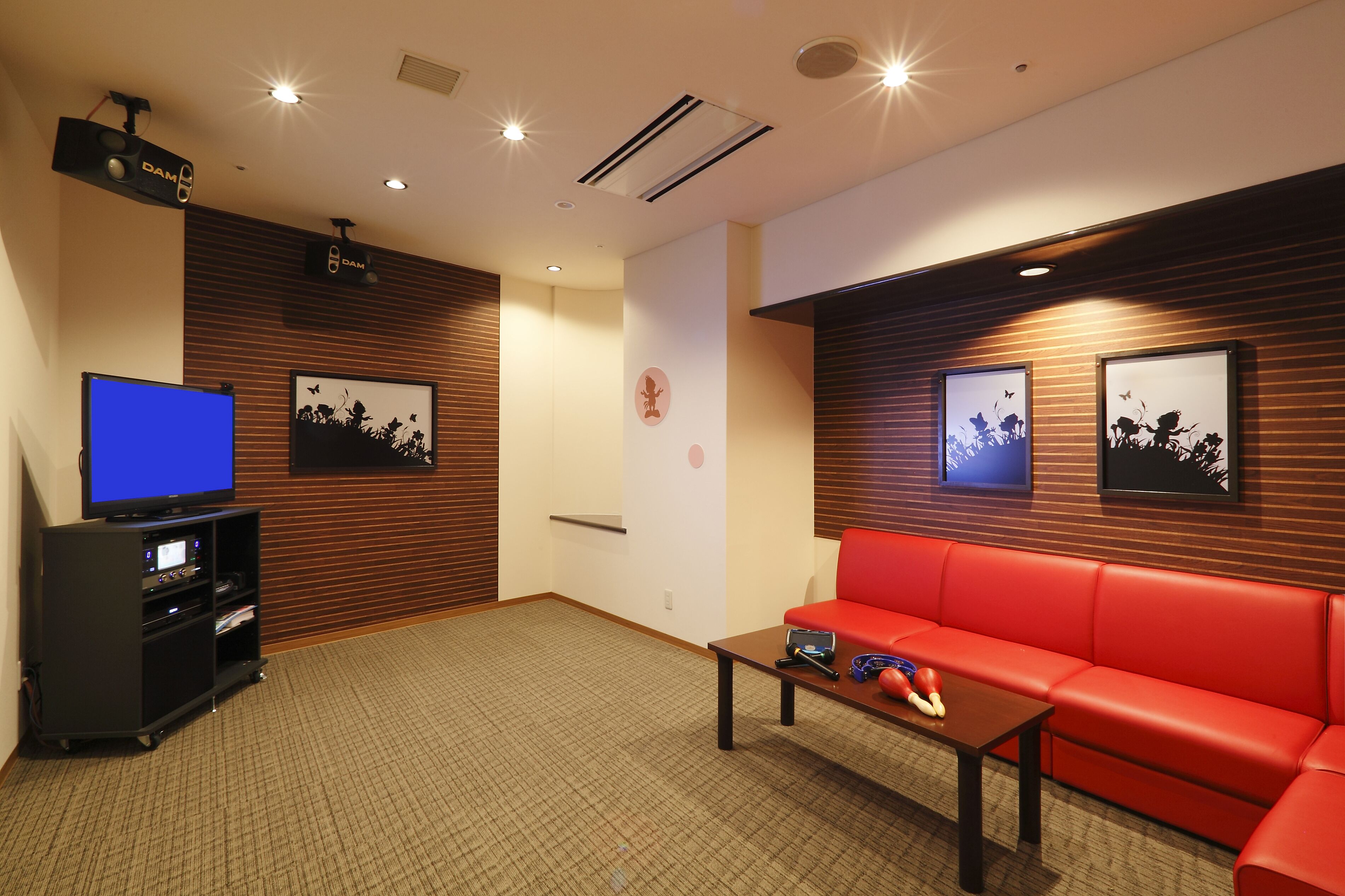 A room with a red sofa, a television, and a small table with a remote control.