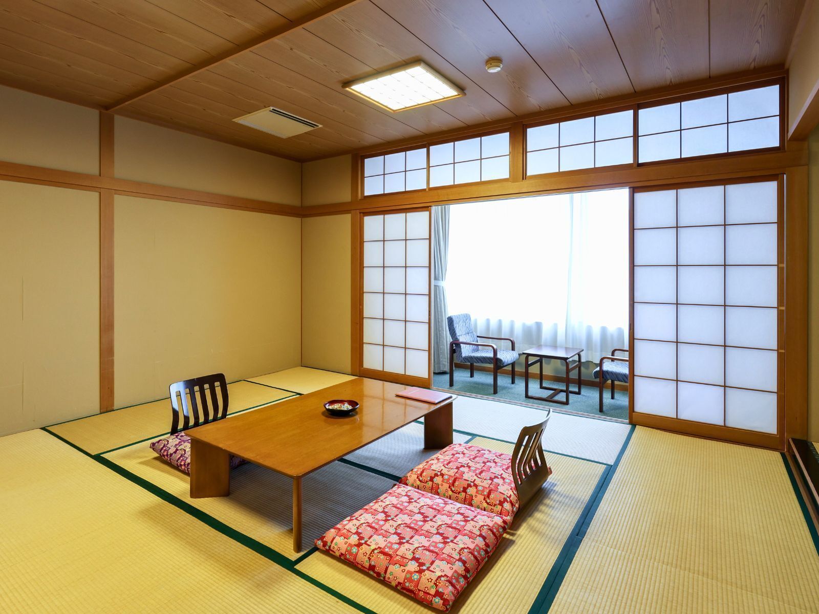 Una habitación japonesa tradicional con suelo de tatami, una mesa baja de madera y paneles de papel shoji.
